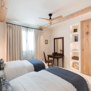 A twin bedroom with marez flooring, hand made wardrobes and an antique desk, mirror and chair in the corner by the windows