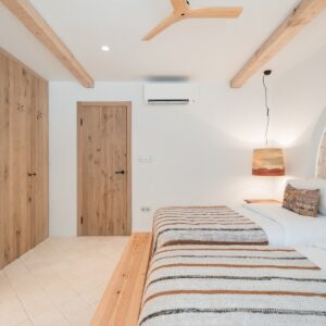 A side view of the twin bedroom with terracotta and beige bed linen, the hand made wooden bedroom door and wardrobes
