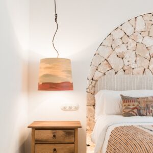 A close up of the hand made bedside table with drop pendant light and the lit recessed arch with a feature stone wall of a twin bedroom
