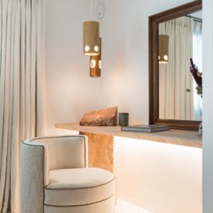 A close up of a hand made stone table with feature stone pillar, mirror and swivel chair in the corner all beautifully lit up in a twin bedroom