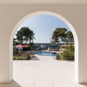 A view of the marez outdoor terrace, through the curved arch colonnade down to the pool of a Menorcan villa