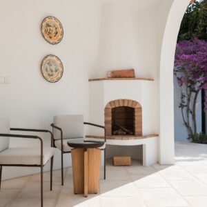 A seating area on the marez outdoor terrace, under the curved arch colonnade and next to the outdoor open fireplace in a Menorcan villa