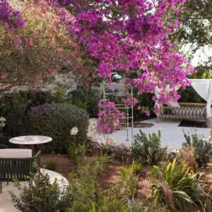 A floriferous view of the gardens and seating area in front of the pool in a Menorcan villa
