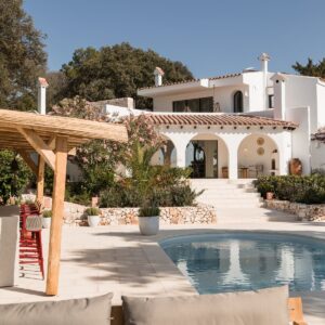 A view from the outdoor terrace looking back the Menorcan villa with a terracotta tile roof and beautiful arched colonnade