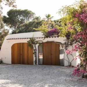 The outdoor accommodation with large hand made wooden doors, framed with a mature bougainvillea at a Menorcan villa