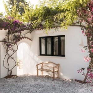An external wall, with a rustic bench, framed with a mature bougainvillea at a Menorcan villa