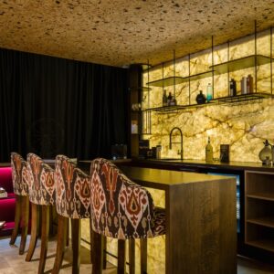A luxury games room with cork ceiling and a back lit stone wall bar with bar stools.