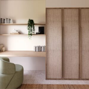 Soft, sunlit 3D render of a Menorcan villa study nook with a floating timber desk, open shelves with books and trailing plant, woven-front wardrobe doors, and a green upholstered chair beside a window with sheer curtains.
