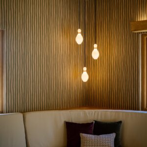 Games room curved banquette seating with timber clad base and warm LED underlighting, beneath 3D-printed duck pin-shaped pendant lights for the duck pin bowling space.
