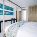 Bedroom featuring commissioned botanical textiles by Turid Ljosnes Tarabay alongside blue-toned artwork by Magda Triay, creating a calm interior shaped by Menorcan artisan craft.