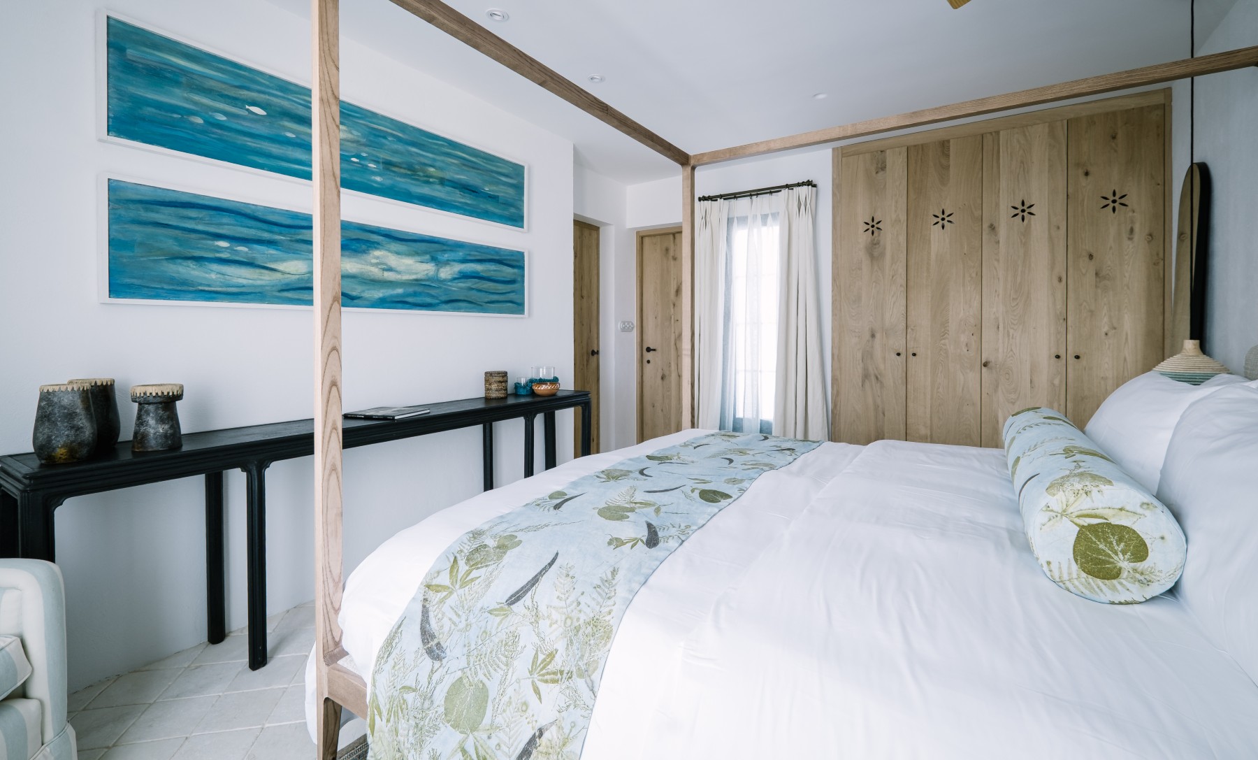 Bedroom featuring commissioned botanical textiles by Turid Ljosnes Tarabay alongside blue-toned artwork by Magda Triay, creating a calm interior shaped by Menorcan artisan craft.